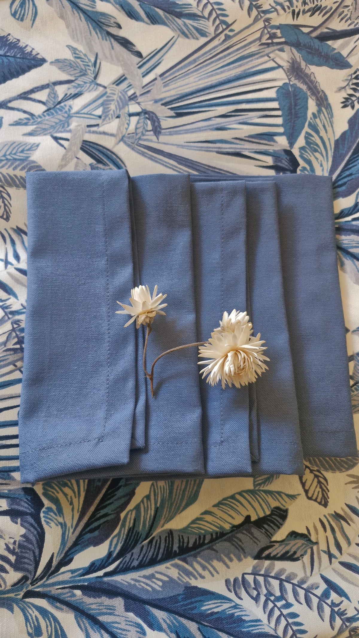 Set de 4 servilletas repelentes azul piedra desplegadas, con flores secas blancas