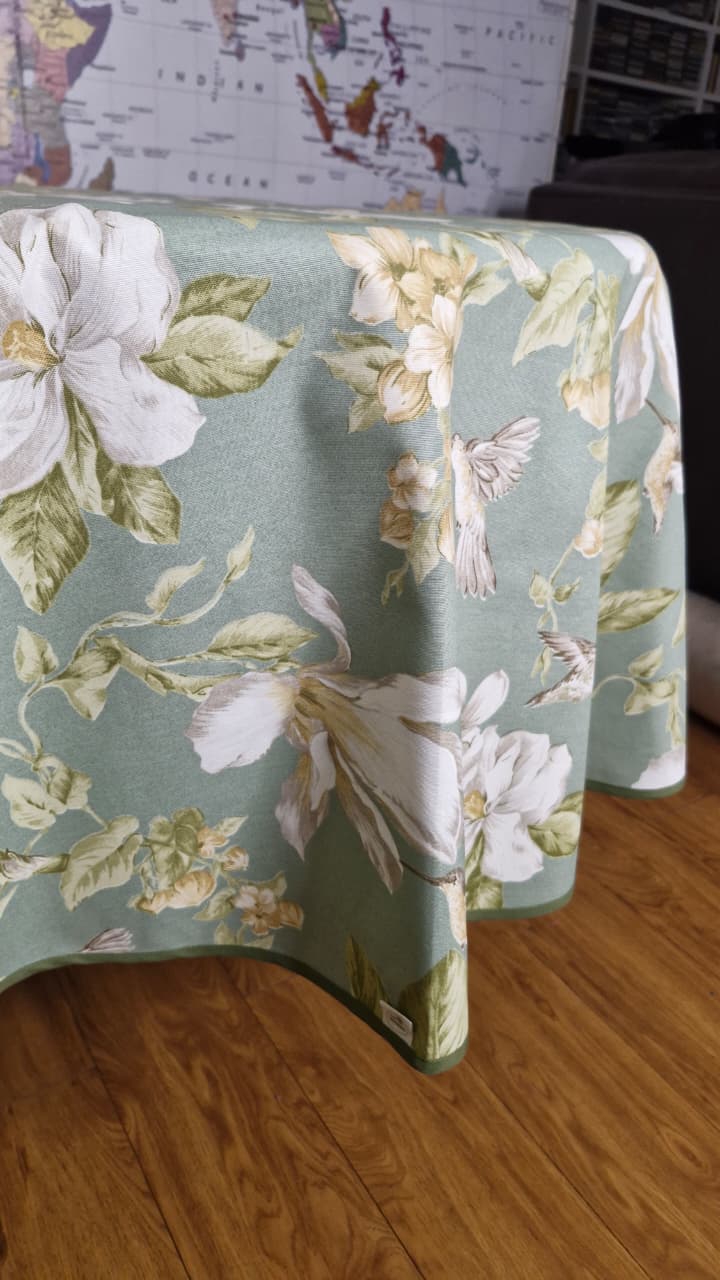 Detalle de la tela repelente con picaflores y flores sobre fondo verde menta